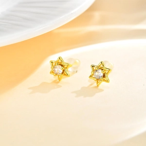 Détail de boucles d'oreilles étoile dorée avec zircon sur un fond épuré chaud