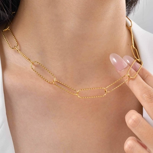 Detailed close-up of a gold hammered textured paperclip chain necklace on a model