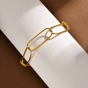 Detail of gold textured rectangular link chain necklace on a white minimalist display stand