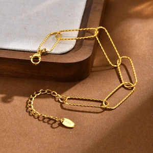 Macro detail of 18K gold textured rectangular link chain with secure lobster clasp and tag