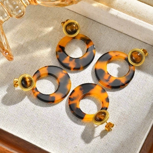 Close-up of gold stud earrings with tiger eye stone and tortoiseshell resin hoop charms