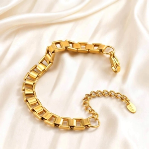 Golden bar link stainless steel bracelet with K18 tag on elegant silk background