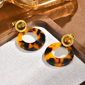 Detailed close-up of gold round earrings with tiger eye stone and leopard print resin