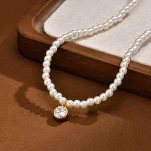 Close-up of white pearl necklace with a round sparkling zircon pendant in gold setting