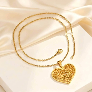 Golden hollow heart tree of life pendant necklace displayed on beige silk fabric