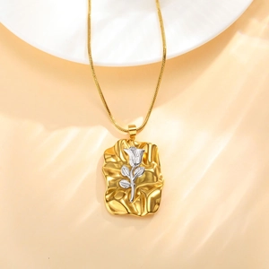 Vue détaillée d'un pendentif carré bicolore avec une rose argentée sur un socle doré texturé