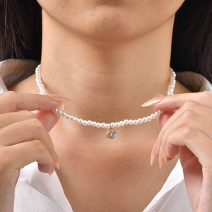 Close-up of pearl necklace with a central round zircon pendant on a model neck