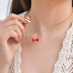 Collier cerise doré élégant avec pendentifs cœurs rouges et nœud sur un mannequin