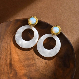 Detail of vintage gold earrings with opal top and white marble acetate rings in a wooden tray
