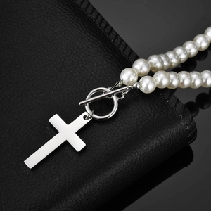 Detail of cross pendant and OT buckle on faux pearl necklace with silver steel finish