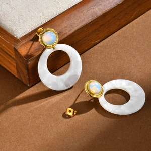 Detail of vintage gold earrings featuring iridescent gems and white marble resin rings