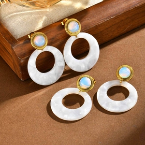 Macro view of gold-plated earrings with iridescent stones and large white round pendants