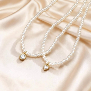 Elegant beaded pearl necklace with gold heart and round zircon pendants on satin