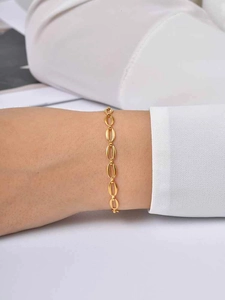 Primo piano di un braccialetto a catena dorato minimalista indossato da una donna