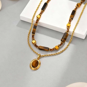Vue détaillée du collier double épaisseur avec pendentif œil de tigre et chaîne dorée
