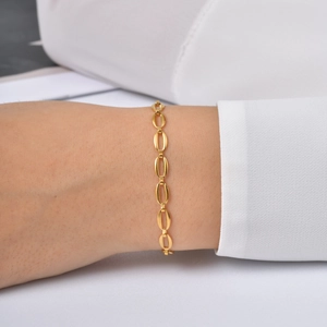 Dettaglio del bracciale minimalista placcato oro a maglie ovali su polso elegante