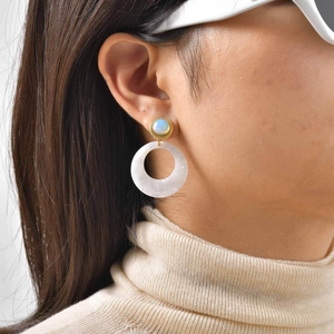 Detail of vintage gold earrings with white opal stud and marble-textured resin ring