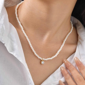 Minimalist pearl necklace with golden heart zircon pendant on female model