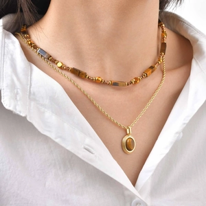 Détail d'un collier doré à double rangée avec pendentif en œil de tigre naturel