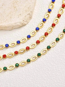 Detailopname van gouden kettingschakels met rode, blauwe en groene strass-steentjes