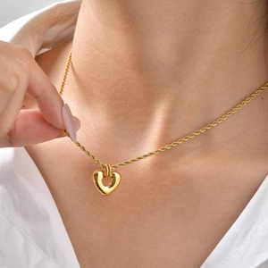Détail d'un collier chaîne torsadée en or 18 carats avec pendentif cœur poli pour femme