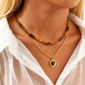 Détail du collier double rang avec chaîne dorée et pendentif en pierre oeil de tigre