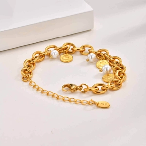 Dettaglio del bracciale a maglie dorate con perle e pendenti a forma di moneta