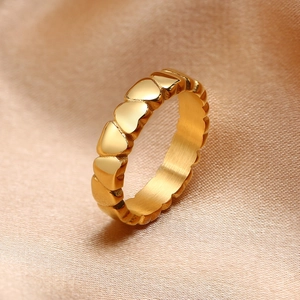 Golden stainless steel heart-shaped ring displayed on luxurious gold satin fabric