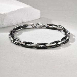 Close-up of polished stainless steel and black ceramic links of a Cuban style bracelet