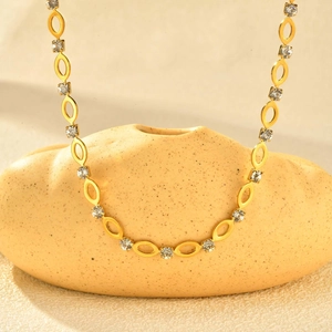Detail van gouden ovale schakelketting met vierkante witte strass-steentjes op keramiek