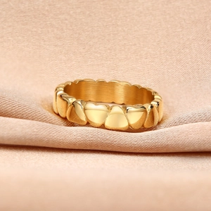 Macro shot of gold heart-shaped stacking ring on elegant beige silk fabric background