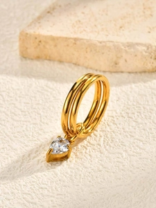 Macro d'une bague triple anneau dorée avec zircon blanc poire sur fond pierre