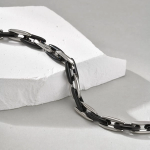 Close-up of industrial silver and black capsule link chain bracelet on stone