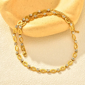 Detail van gouden schakelketting met heldere strass-steentjes en karabijnsluiting