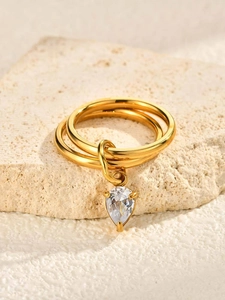 Vue macro d'une bague triple anneau dorée ornée d'un pendentif en zircon en forme de poire