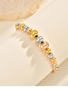 Detailed view of faceted tri-color gold beads on a bracelet showing metallic textures