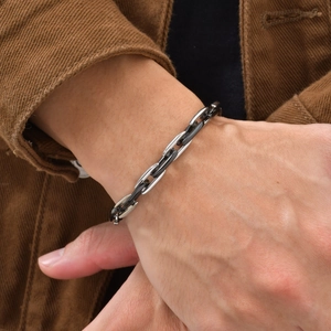 Macro shot of men's two-tone silver and black oval link cuban bracelet on a wrist