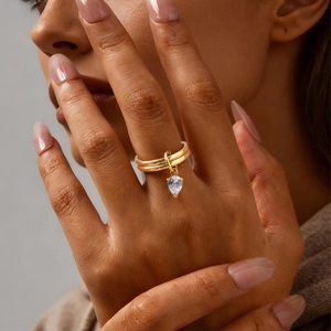 Gros plan d'une bague double dorée avec un pendentif en zircon blanc en forme de poire