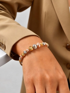 Detailed macro of tricolor metallic beaded bracelet with textured gold silver and rose gold beads