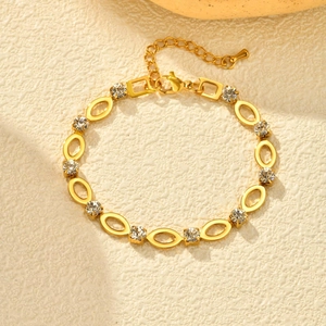 Detail van een vergulde armband met witte strassteentjes en verstelbare karabijnsluiting
