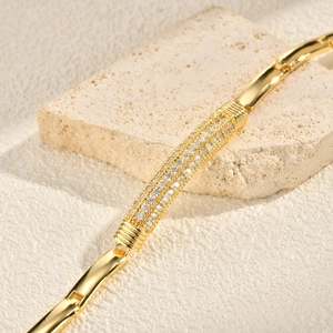 Close-up of a gold-plated bracelet featuring a sparkling zircon-encrusted cylindrical center