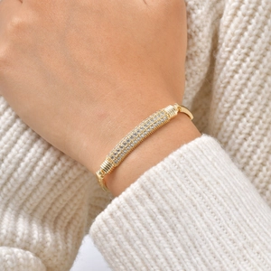 Macro detail of a gold heart bracelet with pavé-set zircons on a knitted sweater background