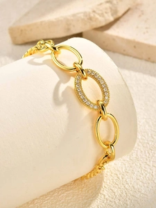 Macro shot of gold oval chain bracelet with micro-pave cubic zirconia on white stone