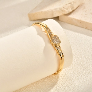 Detail of gold heart bracelet with zircon pavé on a soft minimalist display stand