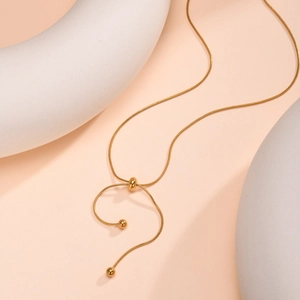 Detail of adjustable gold snake chain necklace with sliding bead and spherical pendants