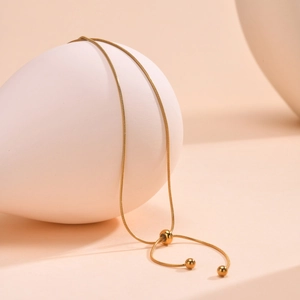 Detail of gold snake chain necklace showing the adjustable slide clasp and bead charms