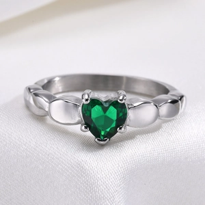 Gros plan d'une bague avec zircon vert en forme de cœur sur tissu de soie
