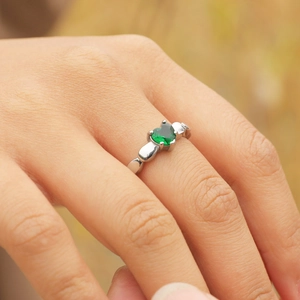 Gros plan d'une bague avec zircon vert en forme de cœur sur anneau en acier inoxydable