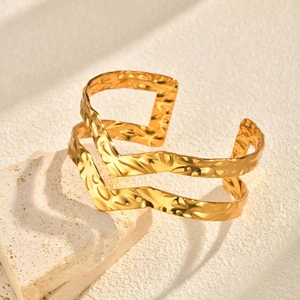Détail d'un bracelet jonc double couche doré avec une texture martelée irrégulière