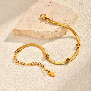 Golden blade chain bracelet with 18K gold-plated 3D roses on textured stone background
